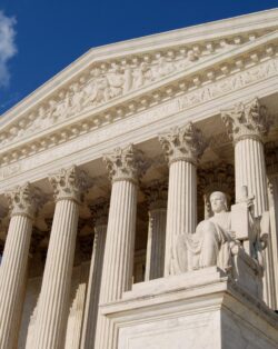 US Supreme Court Building a grand, neoclassical structure with a wide staircase leading up to a row of tall, imposing columns. Above the entrance, the words "Equal Justice Under Law" are inscribed.