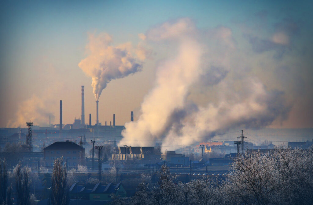 A petrochemical plant with visible smoke rising from its stacks, symbolizing manufacturing processes and pollution.