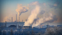 A petrochemical plant with visible smoke rising from its stacks, symbolizing manufacturing processes and pollution.